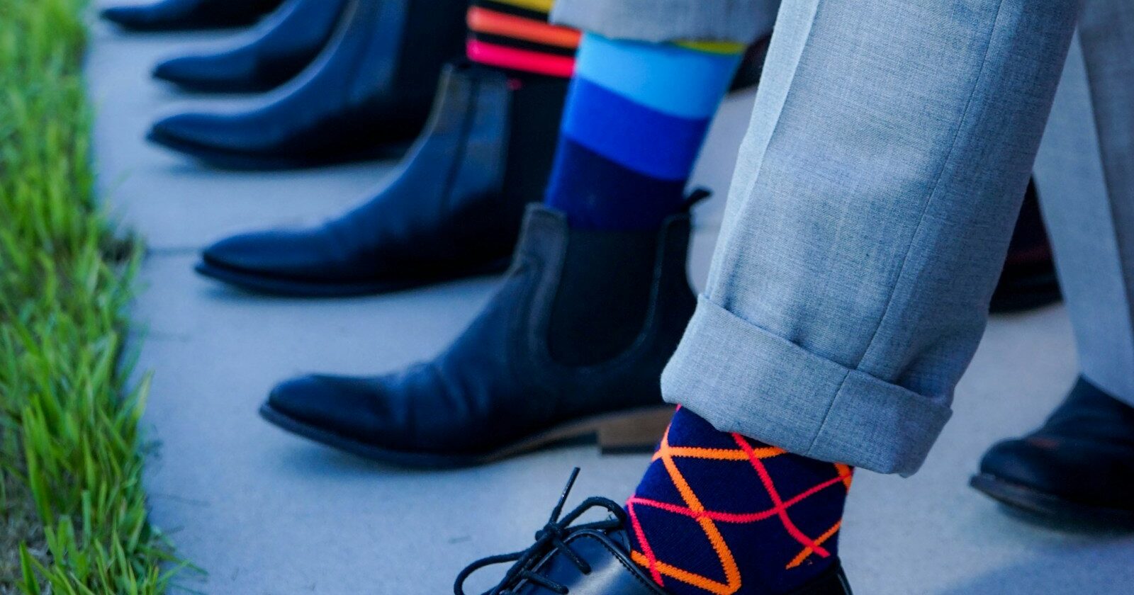 Firmensocken mit Logo an Anzugschuhen, mehrere Personen im Vergleich